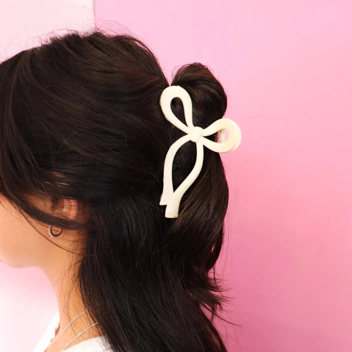 Cream bow hair clip on dark brown hair