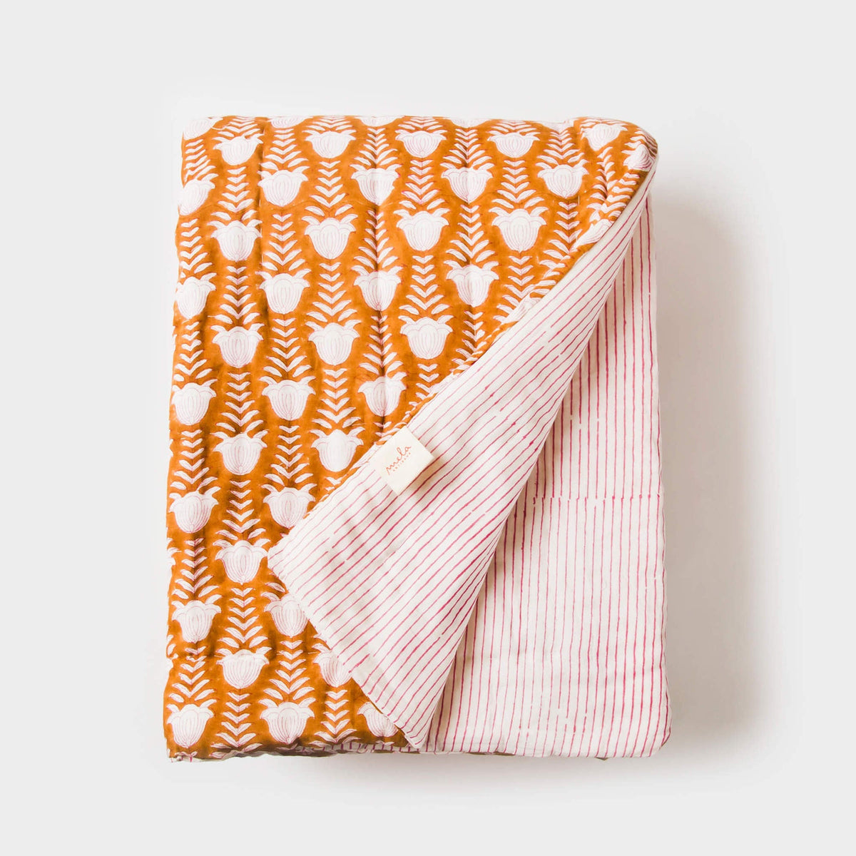 Cotton throw folded: orange leaf pattern with white outlines and pink striped side panel