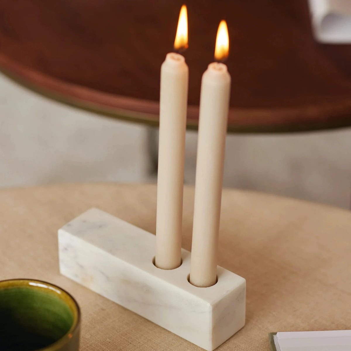 Rectangular marble candle holder holding two lit white pillar candles