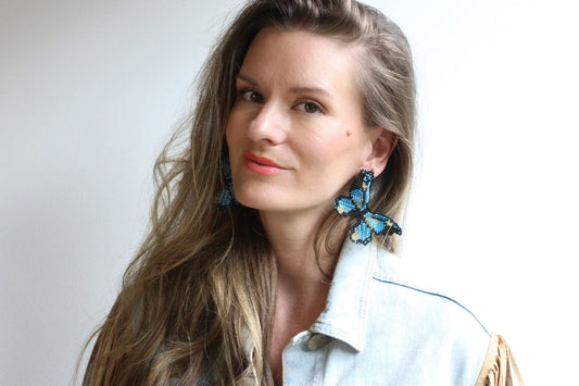 Beaded butterfly earring in blue with black details and gold center, worn
