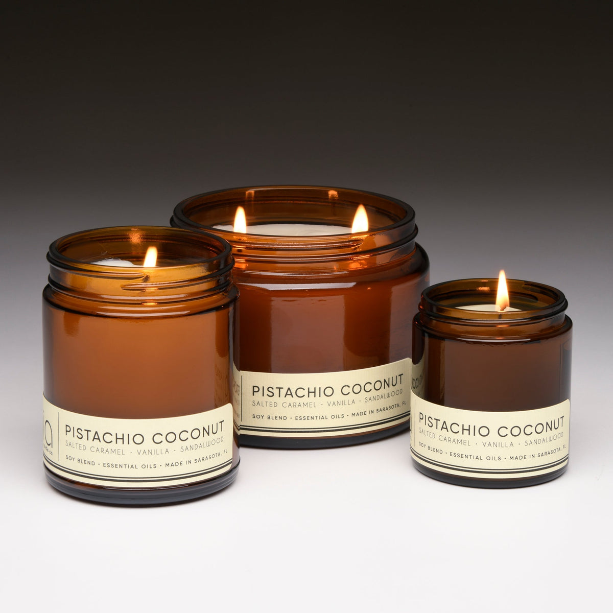 Set of amber glass candles—one large and two small—each with a lit wick