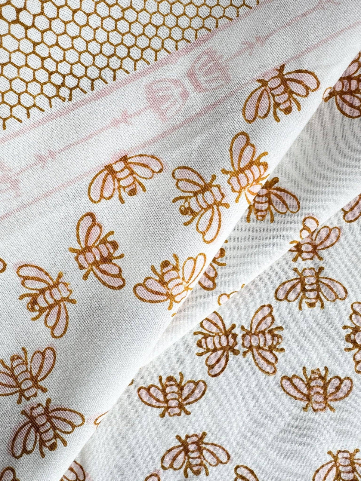 White table throw with scattered honeybee motifs in rose and mustard