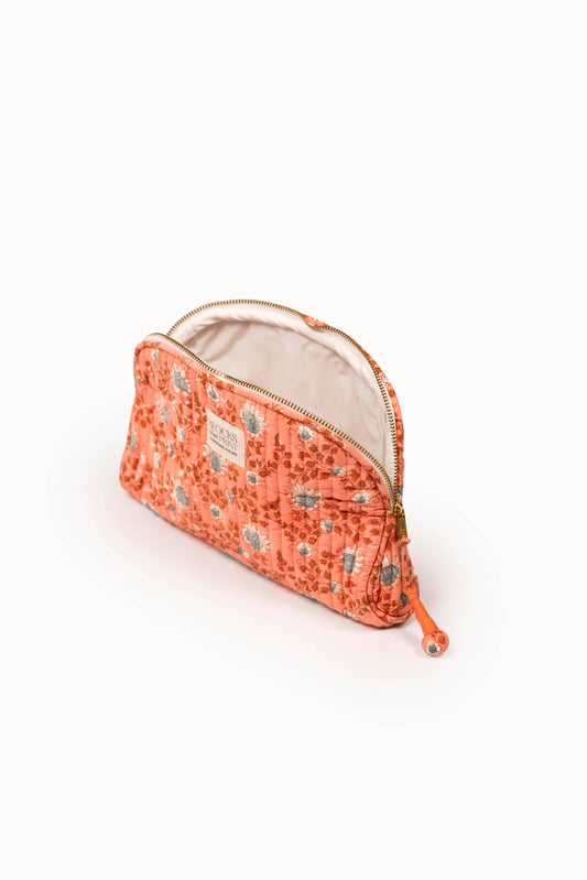Terracotta quilted travel pouch with tan lining, zip closure, and tassel cord