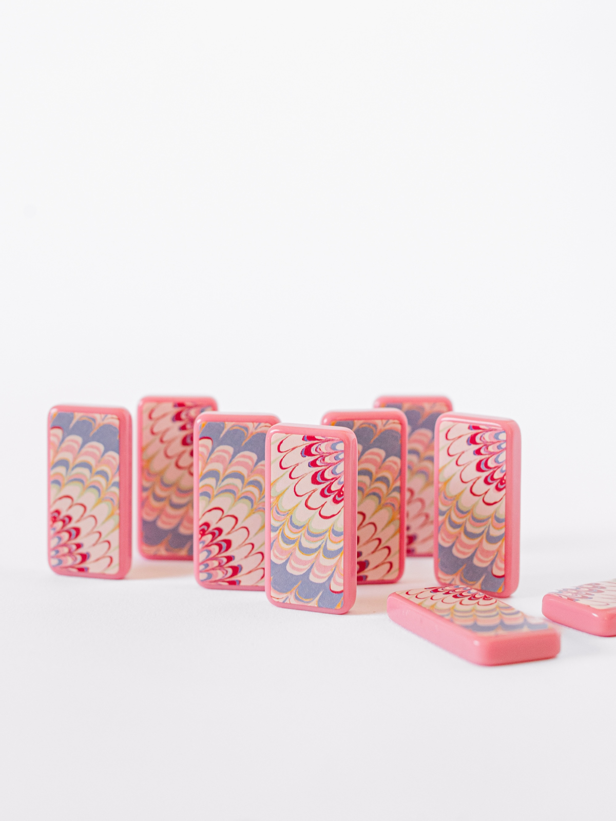 Stack of pink marbled domino tiles with yellow dot pips, side view