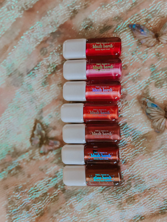 Row of liquid blush bottles with white caps in pink and red shades.