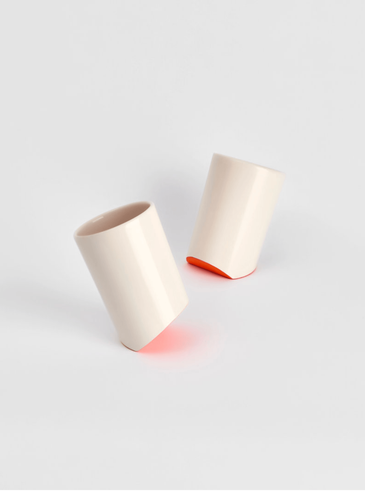 Ceramic cup pair in light cream, one upright and one tilted on the open rim