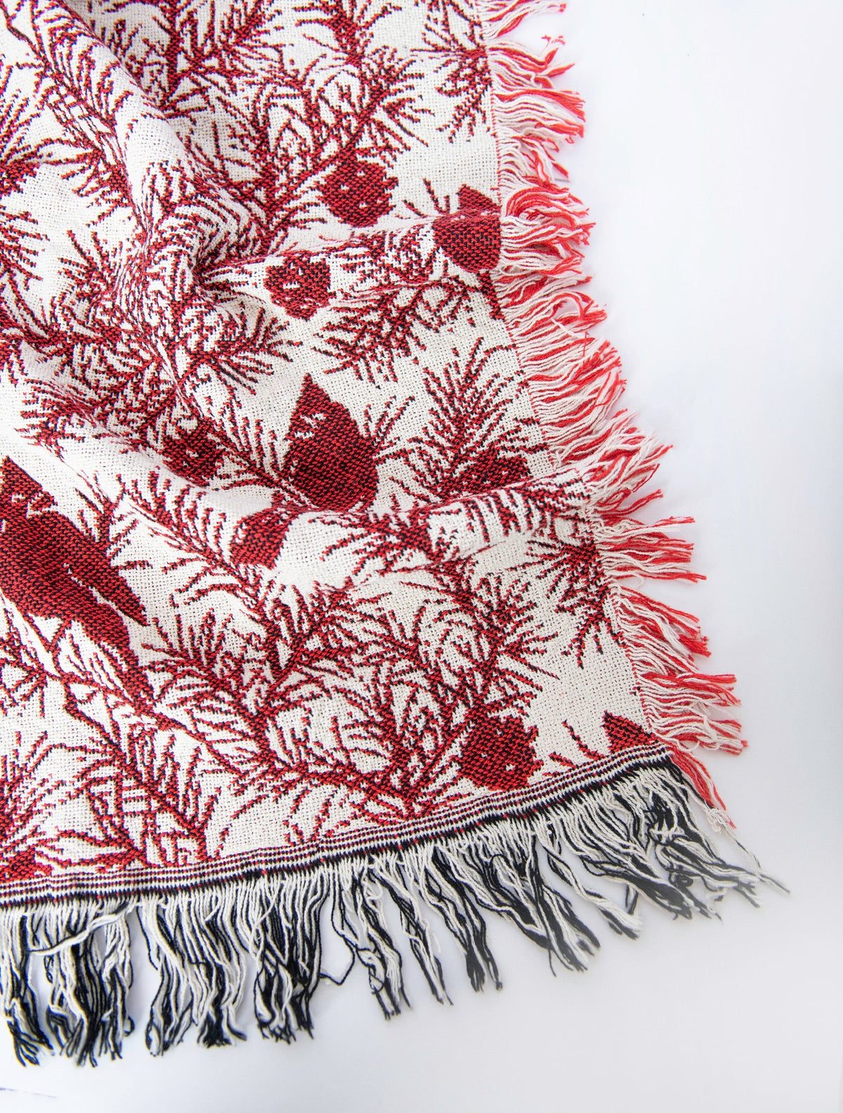 Close-up of red and cream jacquard throw with cardinal pattern and tassel fringe