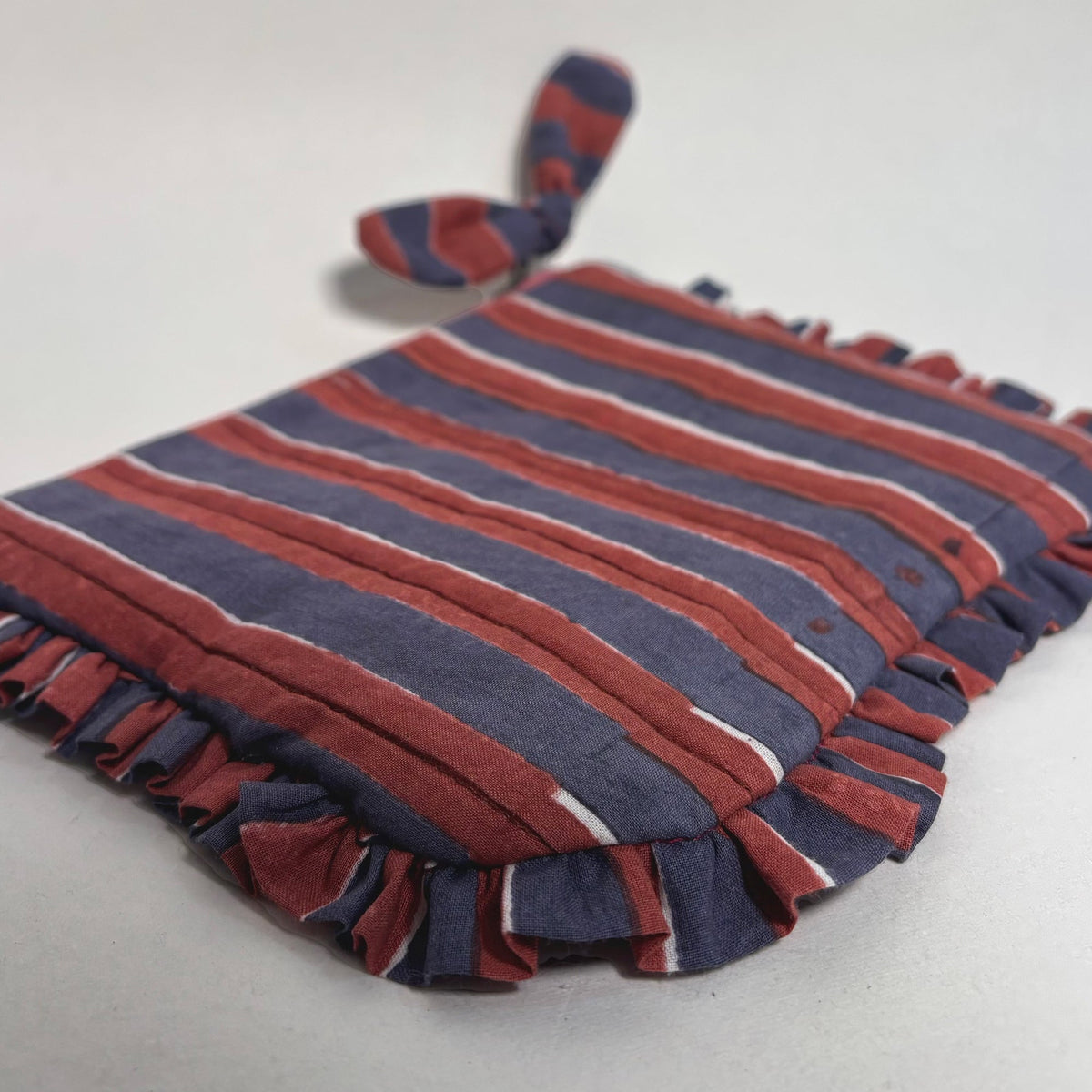 Striped quilted travel pouch with frill trim laid flat, bow tie at top