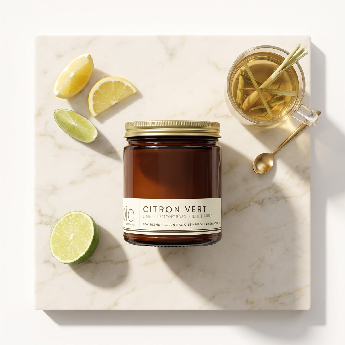 Amber soy blend candle jar with lid and Citron Vert label, with sliced lemons and limes.