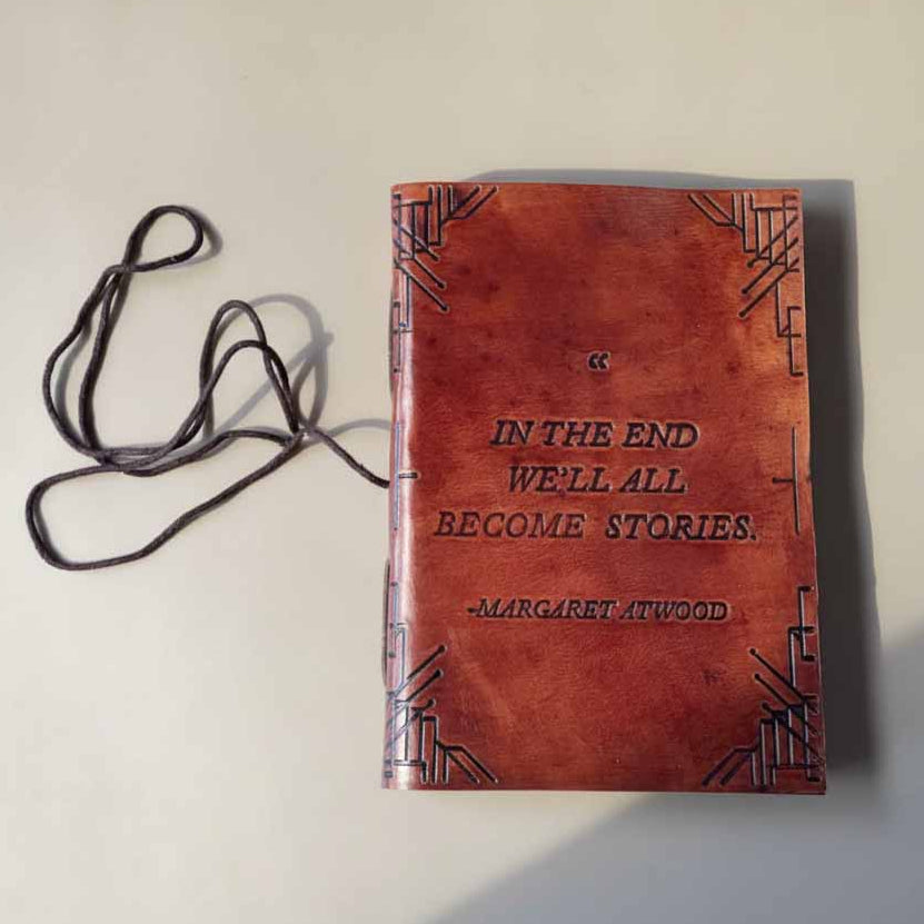 Red-brown leather journal with embossed border and Margaret Atwood quote, tied with black cord