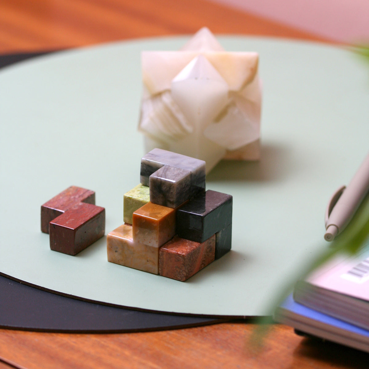 Gemstone cube puzzle with earthy stone blocks and loose cube pieces on a round surface.