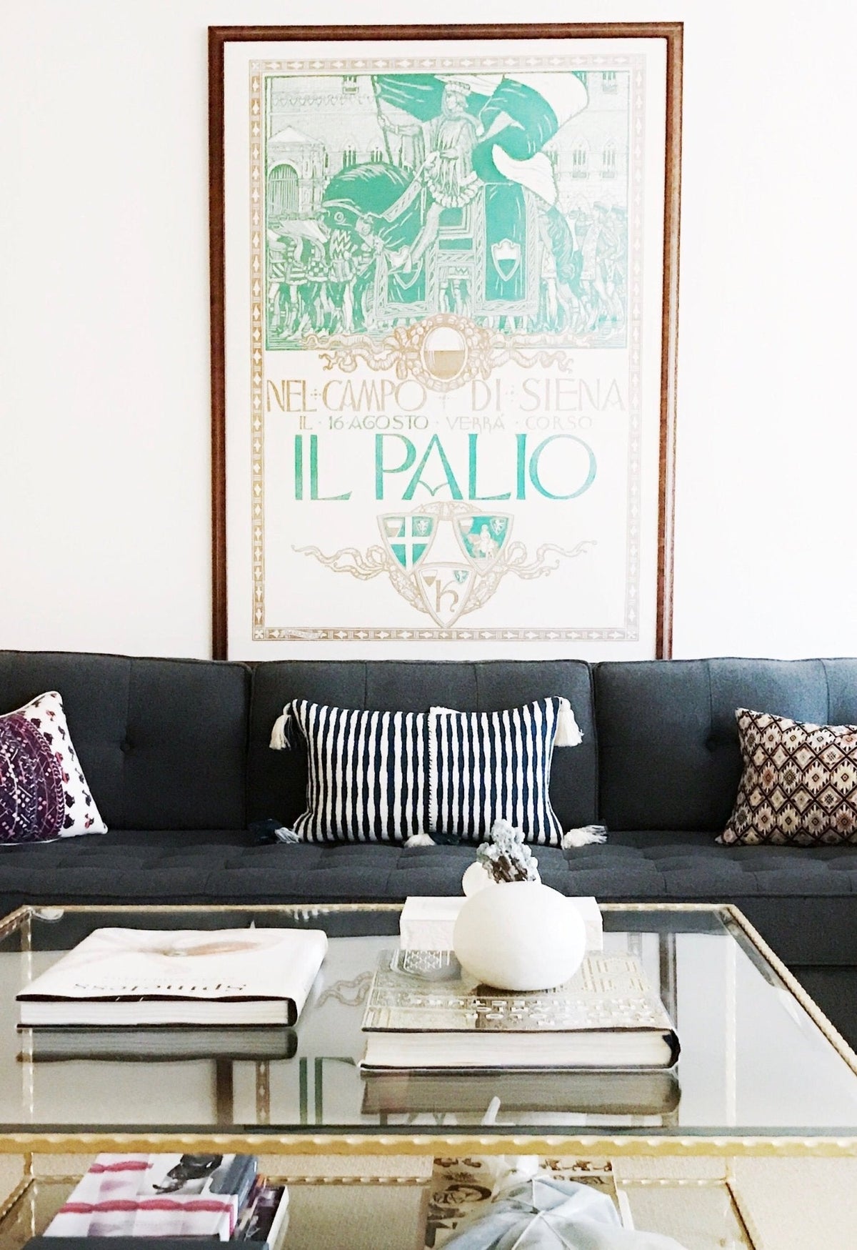 Striped pillow on dark sofa with dark teal and white stripes and tassel corners