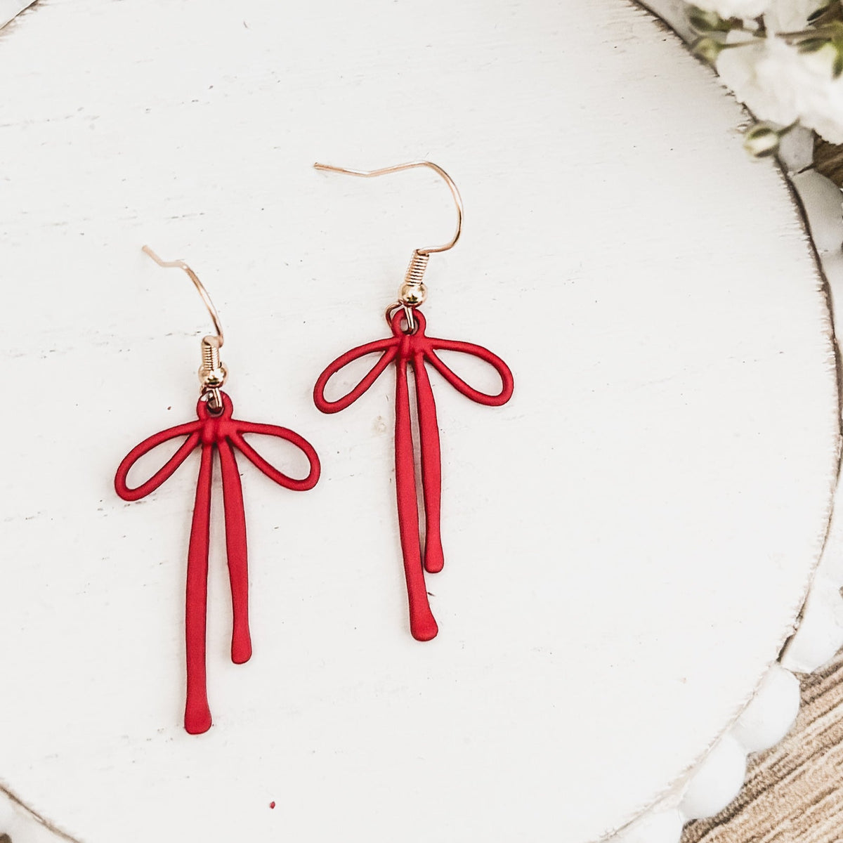 Close-up: red bow drop earrings with tassel strands and gold-tone fishhook backs