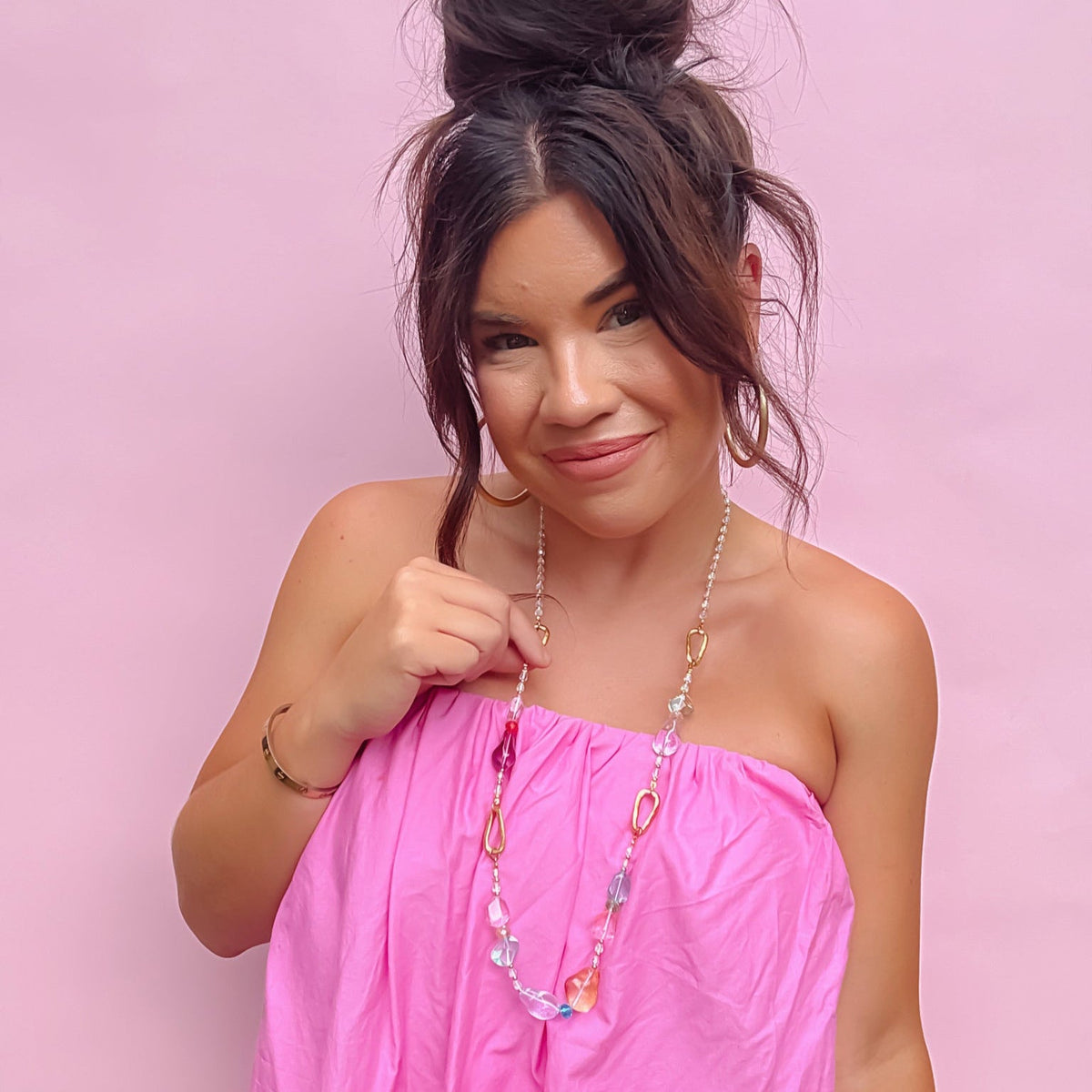 Model wearing pastel beaded necklace with gold chain and pink and clear glass drops.