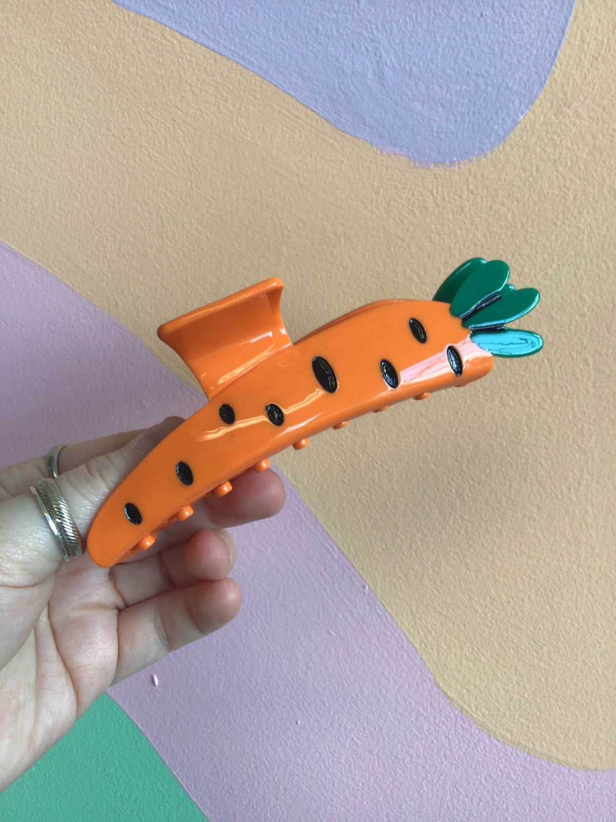 Carrot-shaped hair claw in orange with green leaf top and black dot details