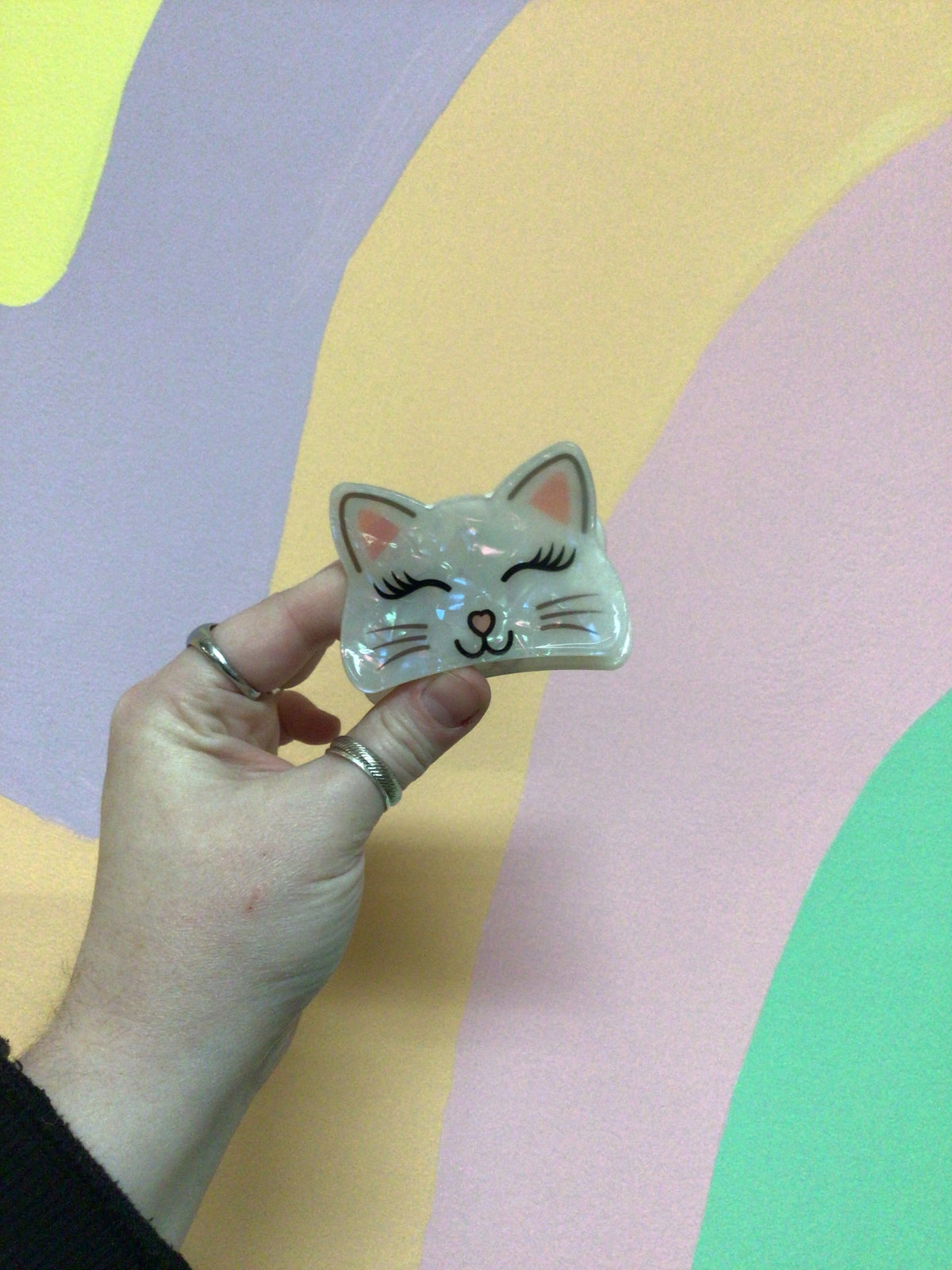 Light gray kitty hair claw with closed-eye face and whisker dot accents