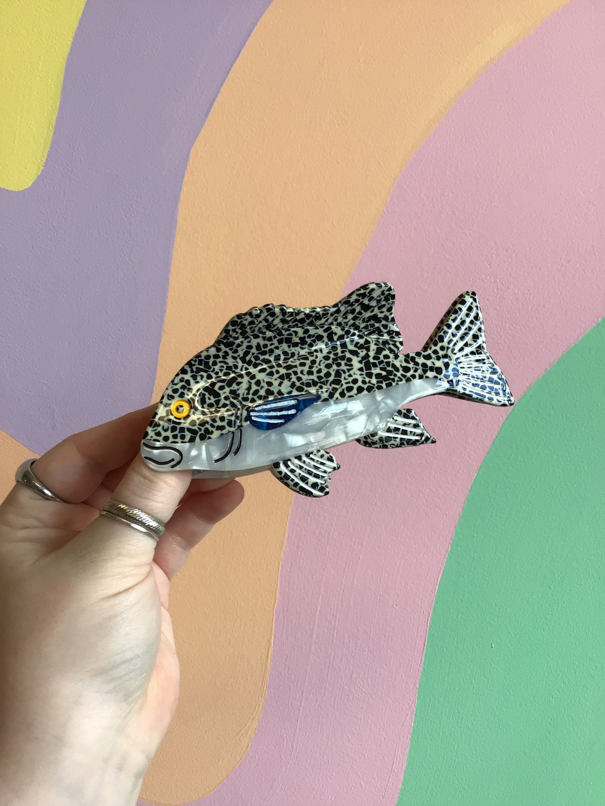 Fish-shaped hair claw with leopard-print body, blue accents, and yellow eye detail