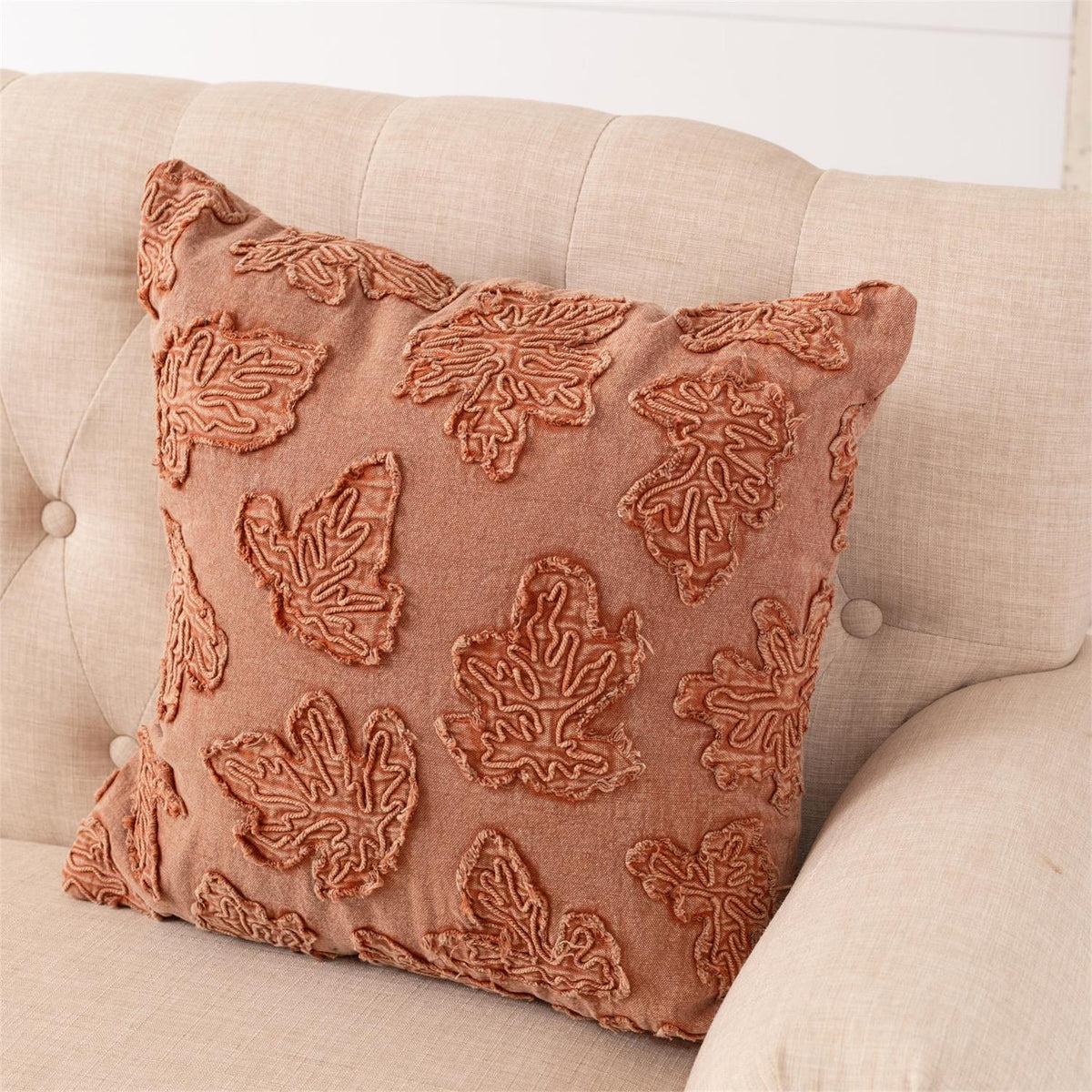 Square throw pillow, rust-orange textured fabric with embroidered leaf motifs
