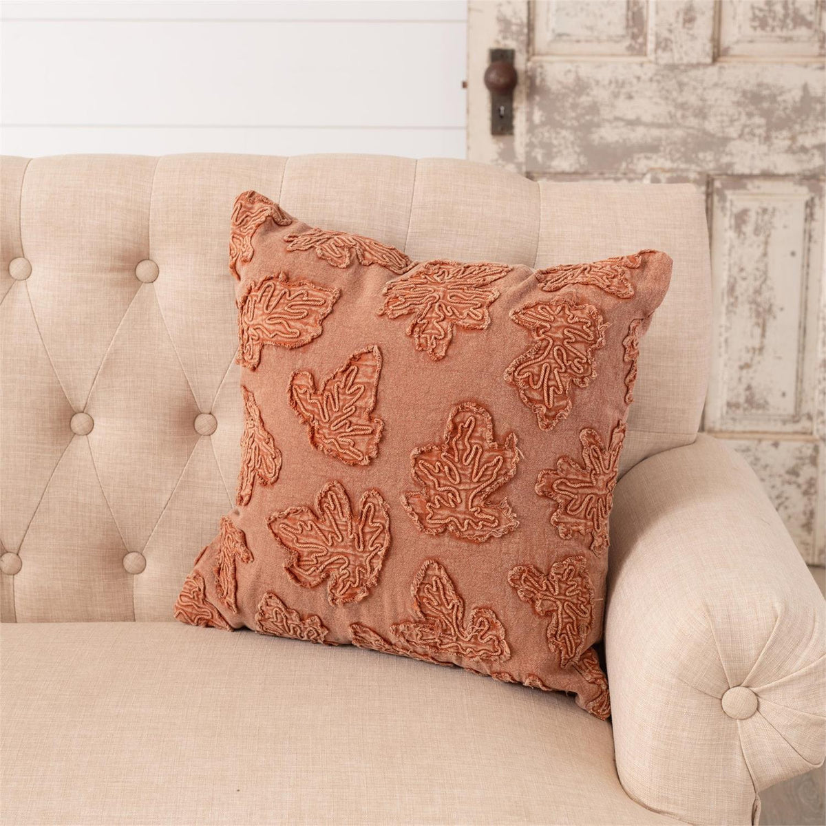 Square throw pillow in rust-orange with textured embroidered leaf pattern