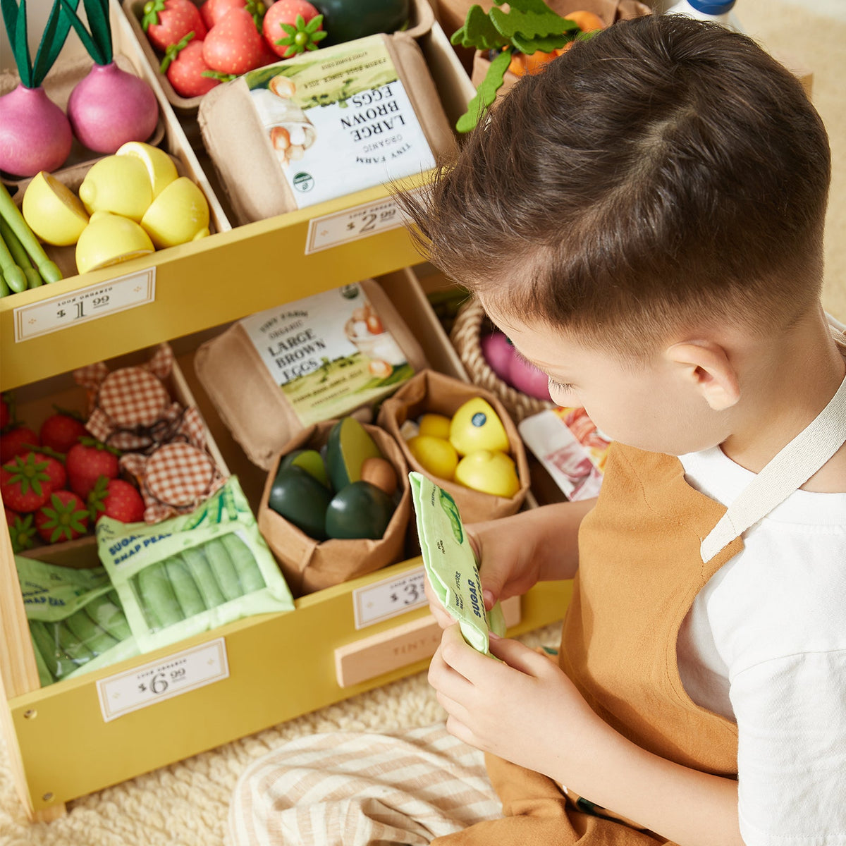 Child sorting toy grocery items from wooden produce crates