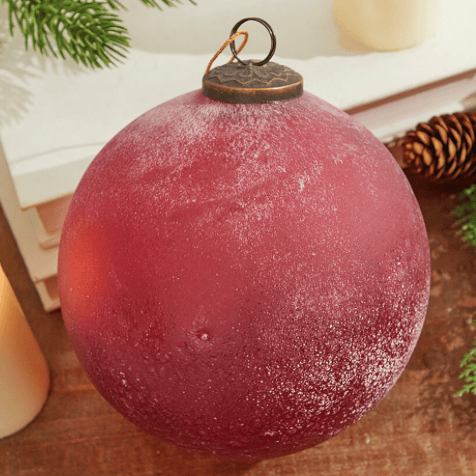 Red frosted glass Christmas ornament ball with gold-tone loop hanger, close-up view.