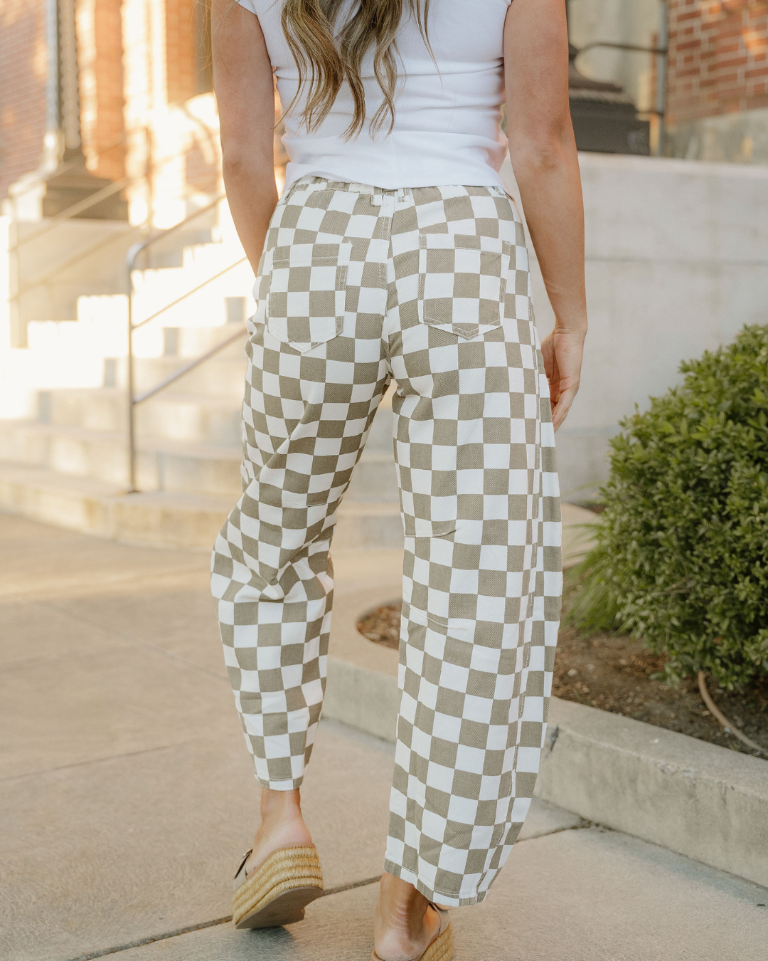 Close-up of sage green and off-white checkered denim barrel pants with belt loops