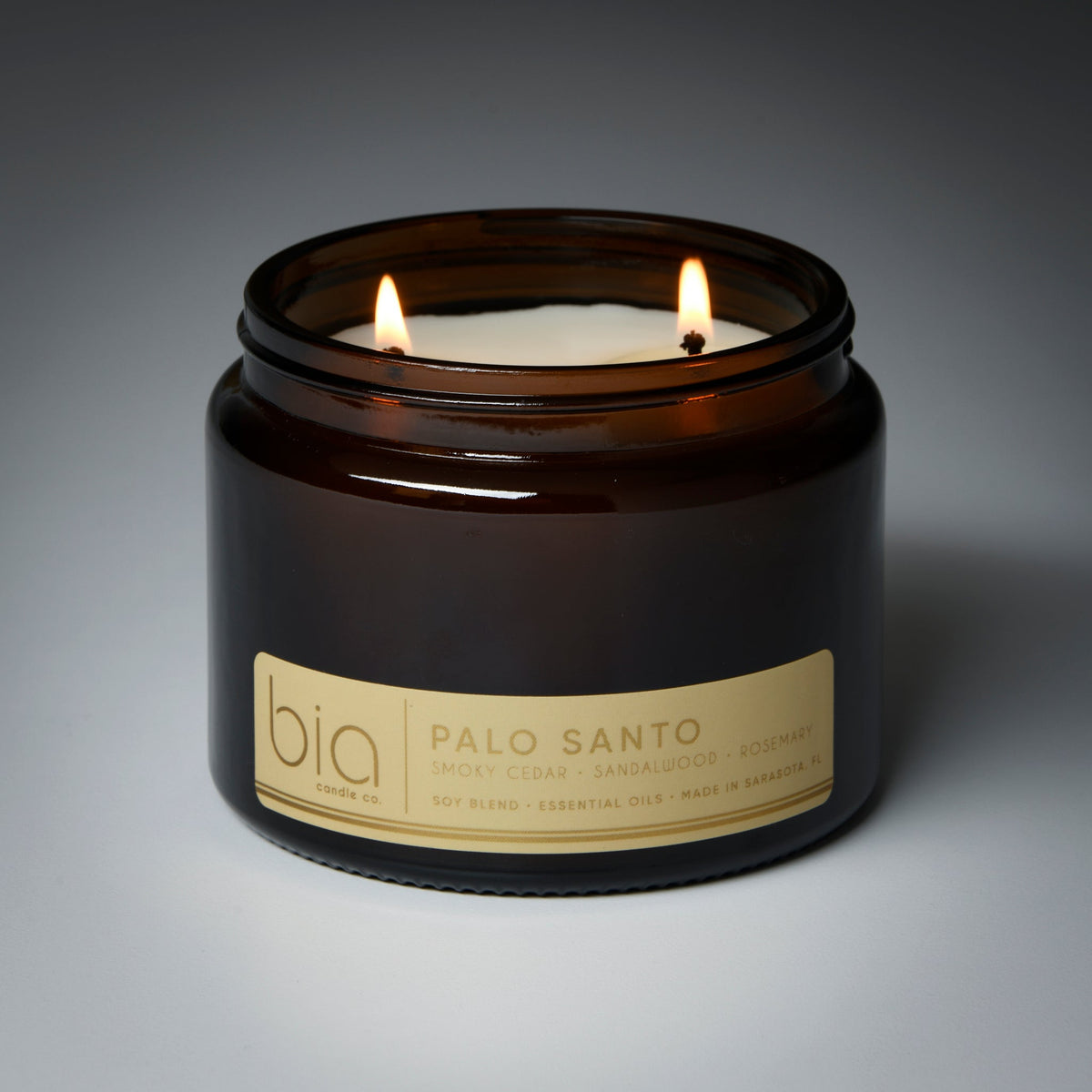Amber glass soy candle jar with burning flame and centered “Palo Santo” label