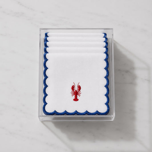 Stack of 6 nautical cocktail napkins in clear holder, white with navy scalloped edge and red lobster