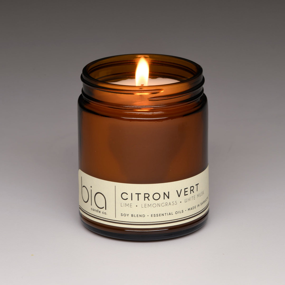 Amber glass soy blend candle with flame and front label reading Citron Vert