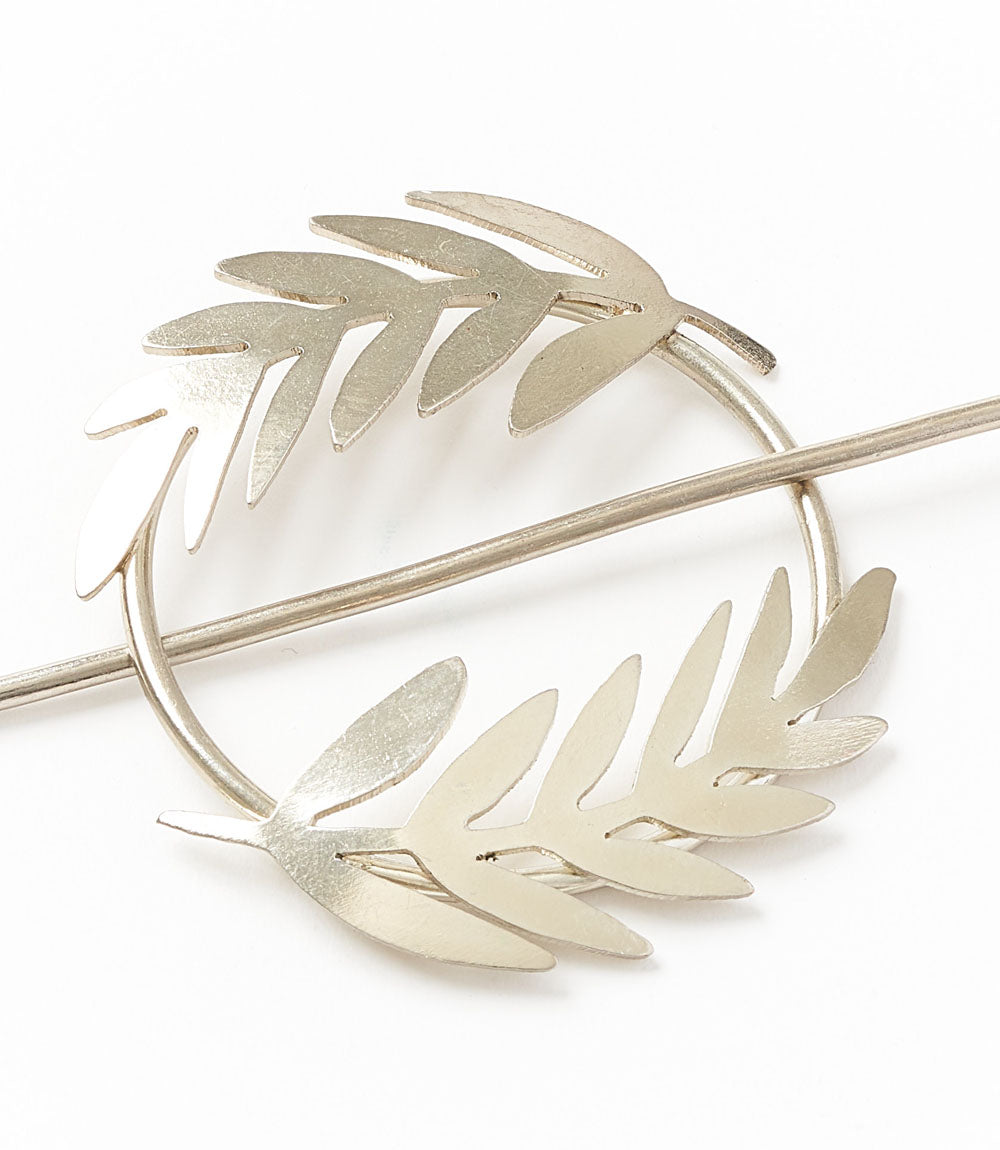 Silver fern hair slide with stick, close-up of curved silver leaf design