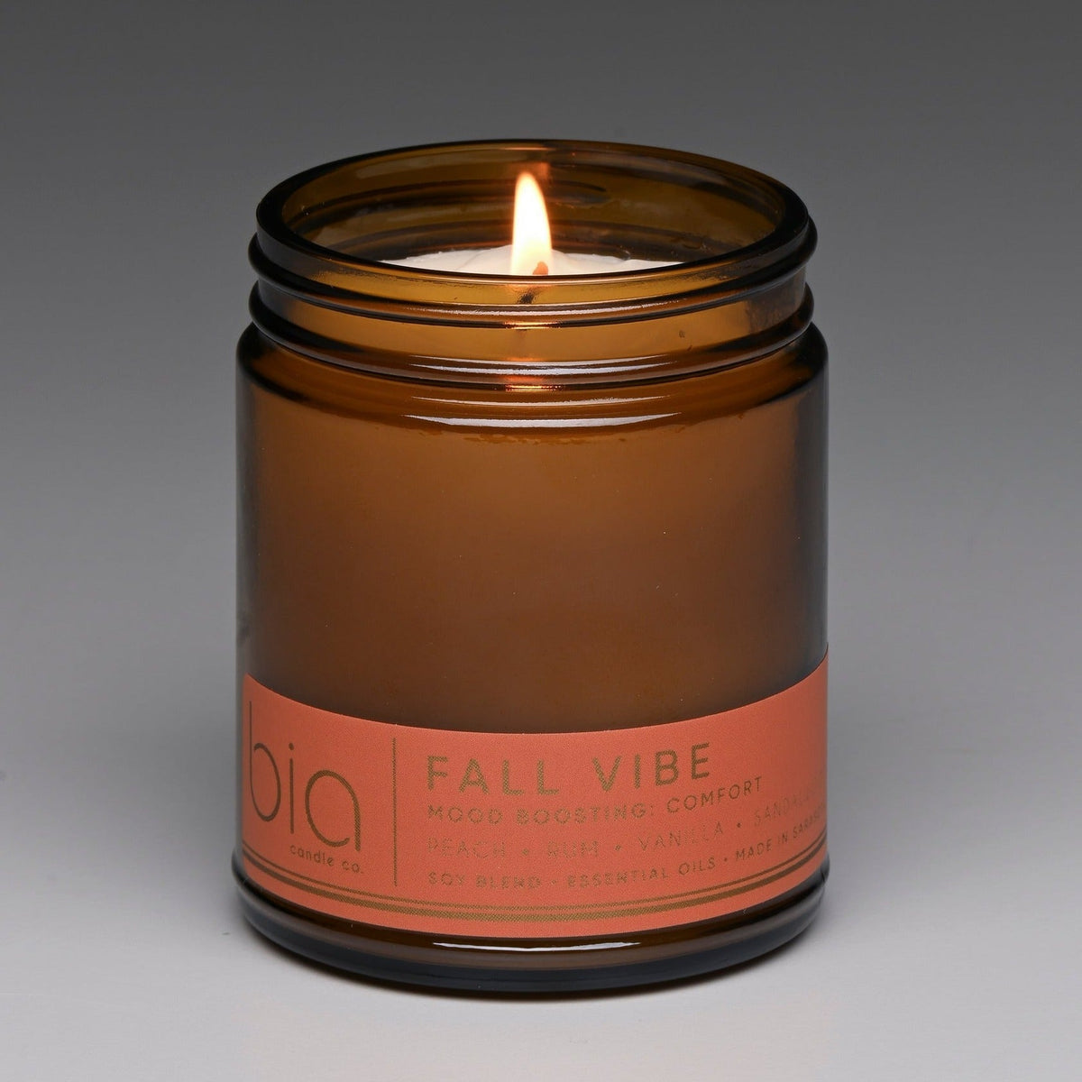 Amber soy blend candle jar with lit wick and 'bio' Fall Vibe label