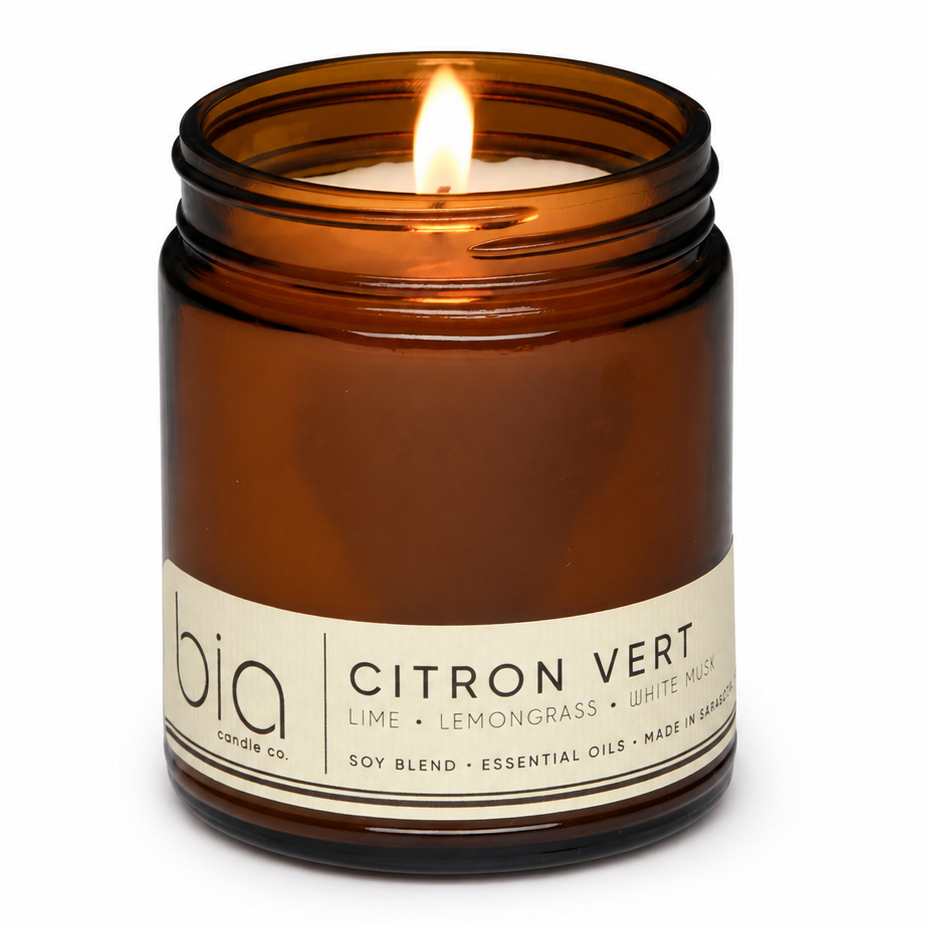 Amber glass soy blend candle jar with lit wick and cream label reading Citron Vert.
