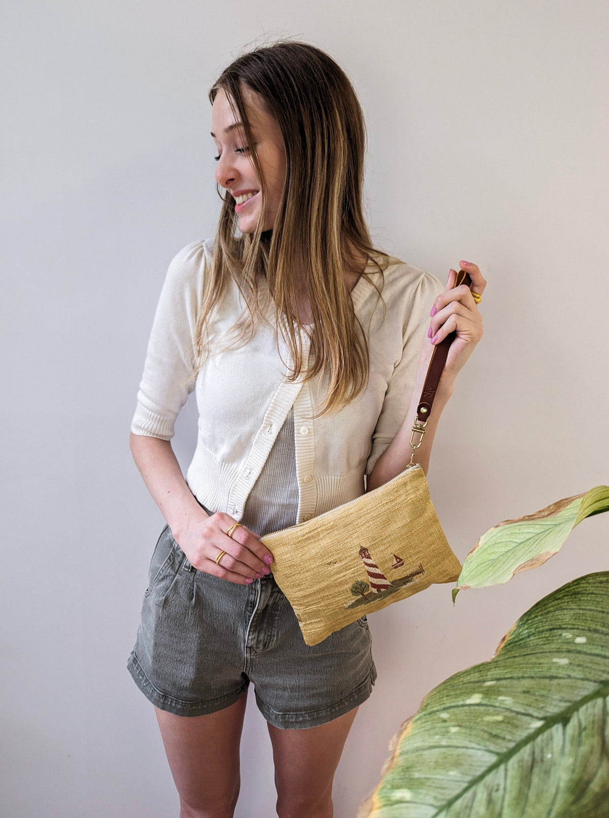 Lighthouse-embroidered linen wristlet worn with its brown leather strap