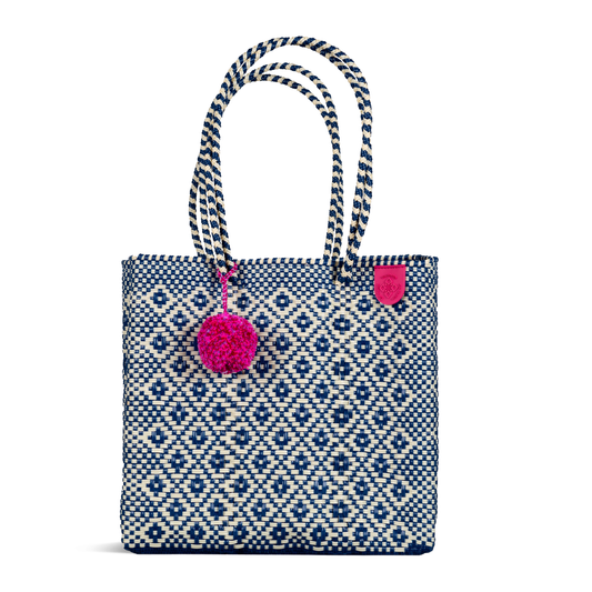 Woven tote bag with blue diamond pattern, striped handles, pink pom-pom charm