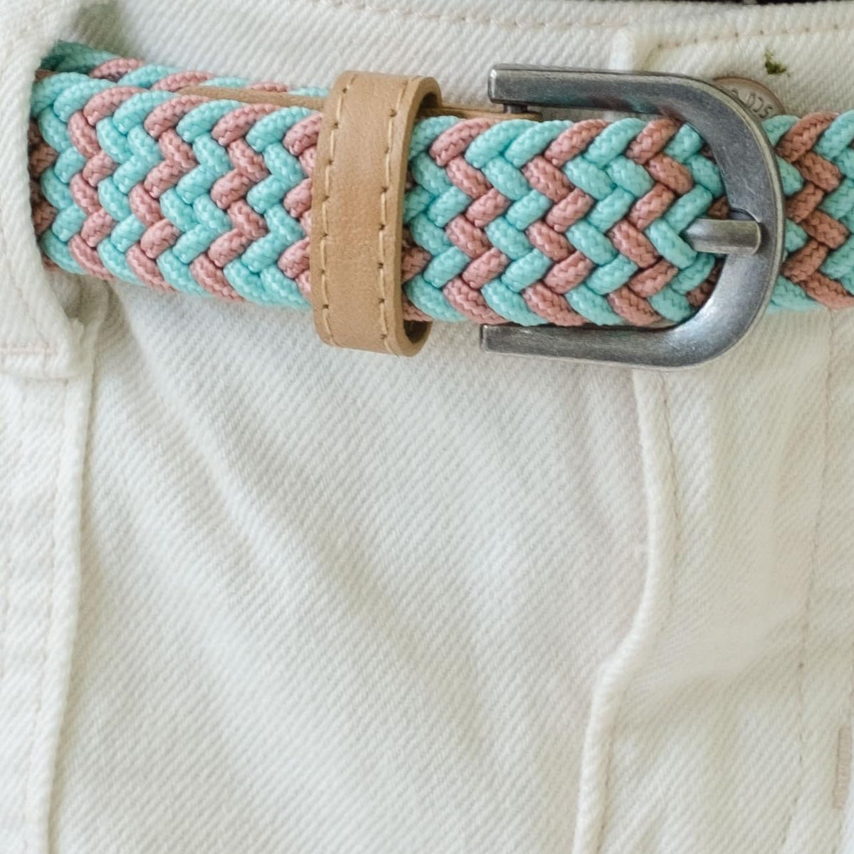 Turquoise and pink braided stretch belt with tan leather loop and metal buckle, worn with white pants