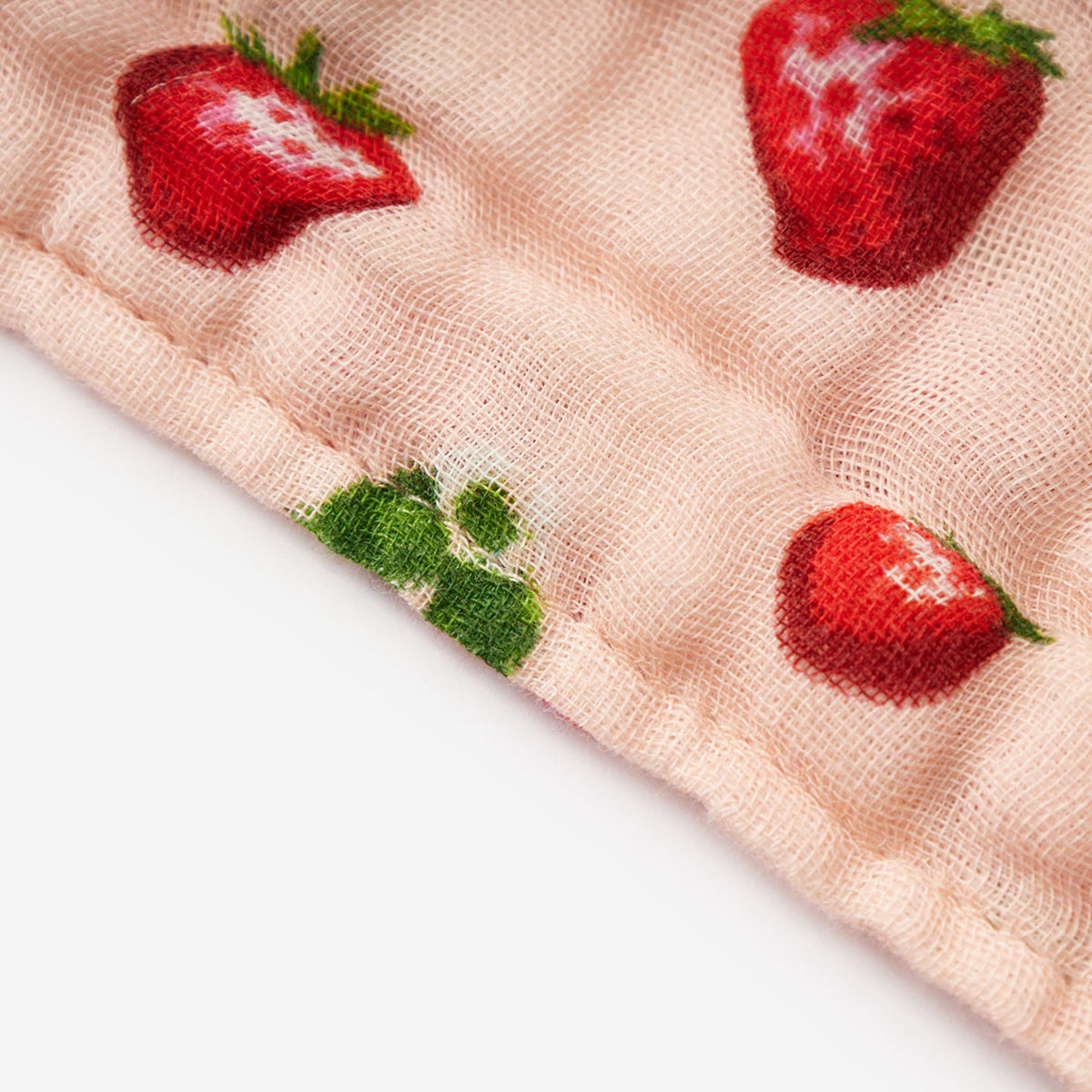 Peach mesh beach towel fabric with red strawberry print and green leaf accents