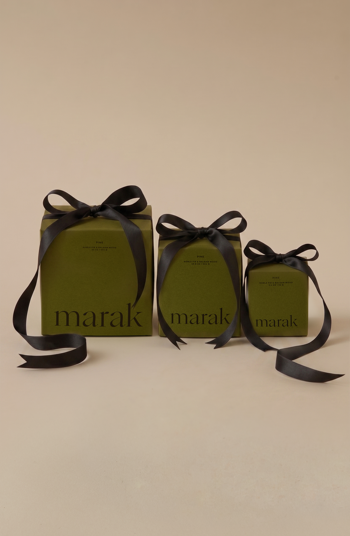 Three marak pine candles in green boxes tied with black ribbon