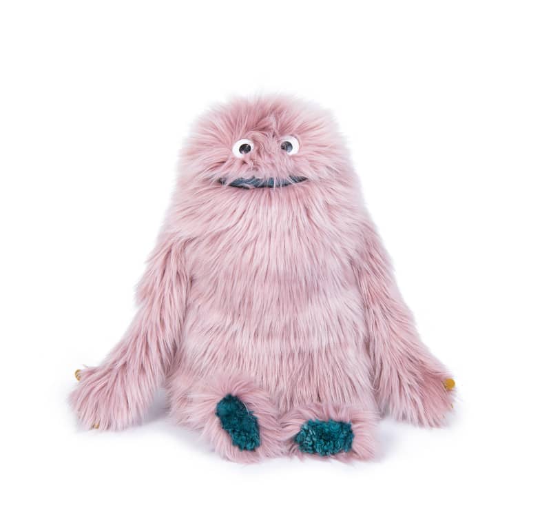 Pink fuzzy stuffed monster toy with big eyes and teal hands and feet.