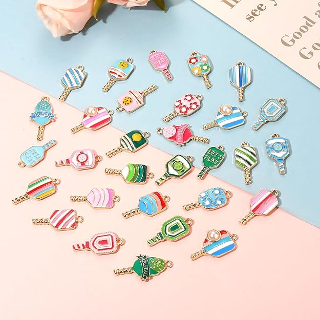 Assorted colorful pickleball charms with striped, floral, paddle, and ball designs and gold-tone loops.