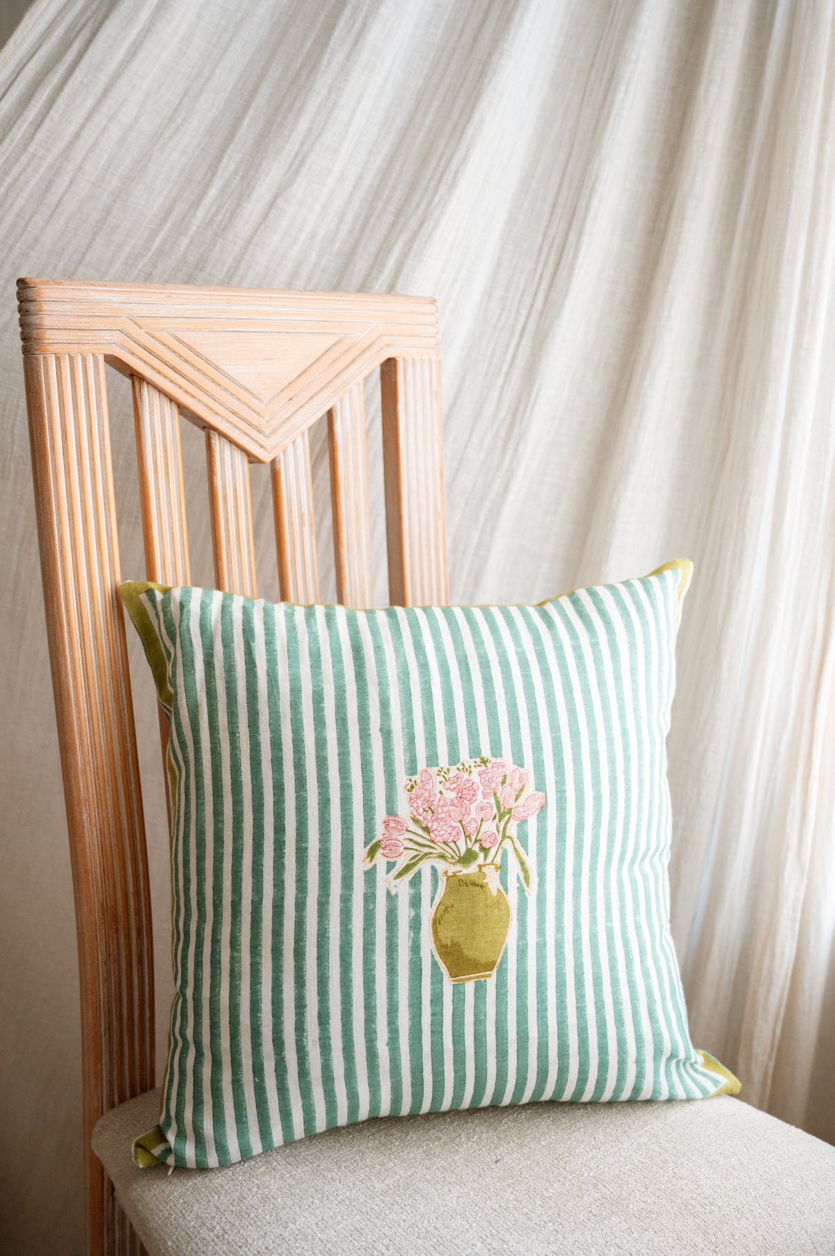 Green striped pillow with floral bouquet applique, shown on an upholstered chair with yellow piping