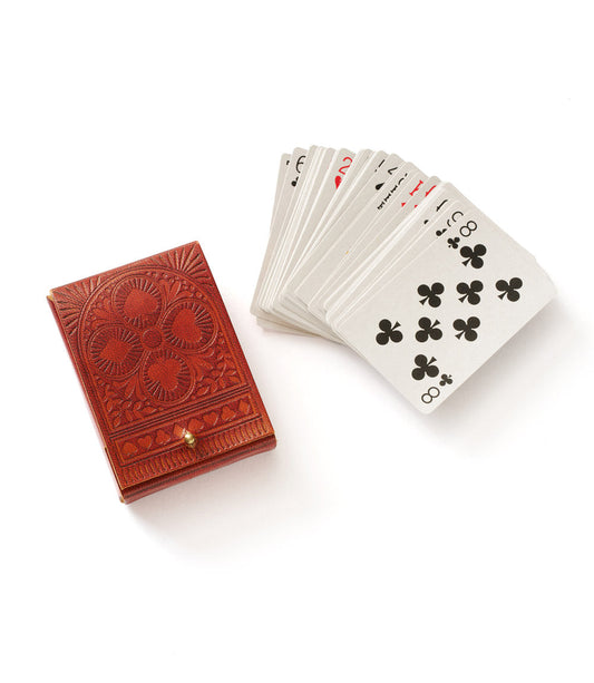 Embossed red leather playing card case with fanned white deck showing club and spade faces