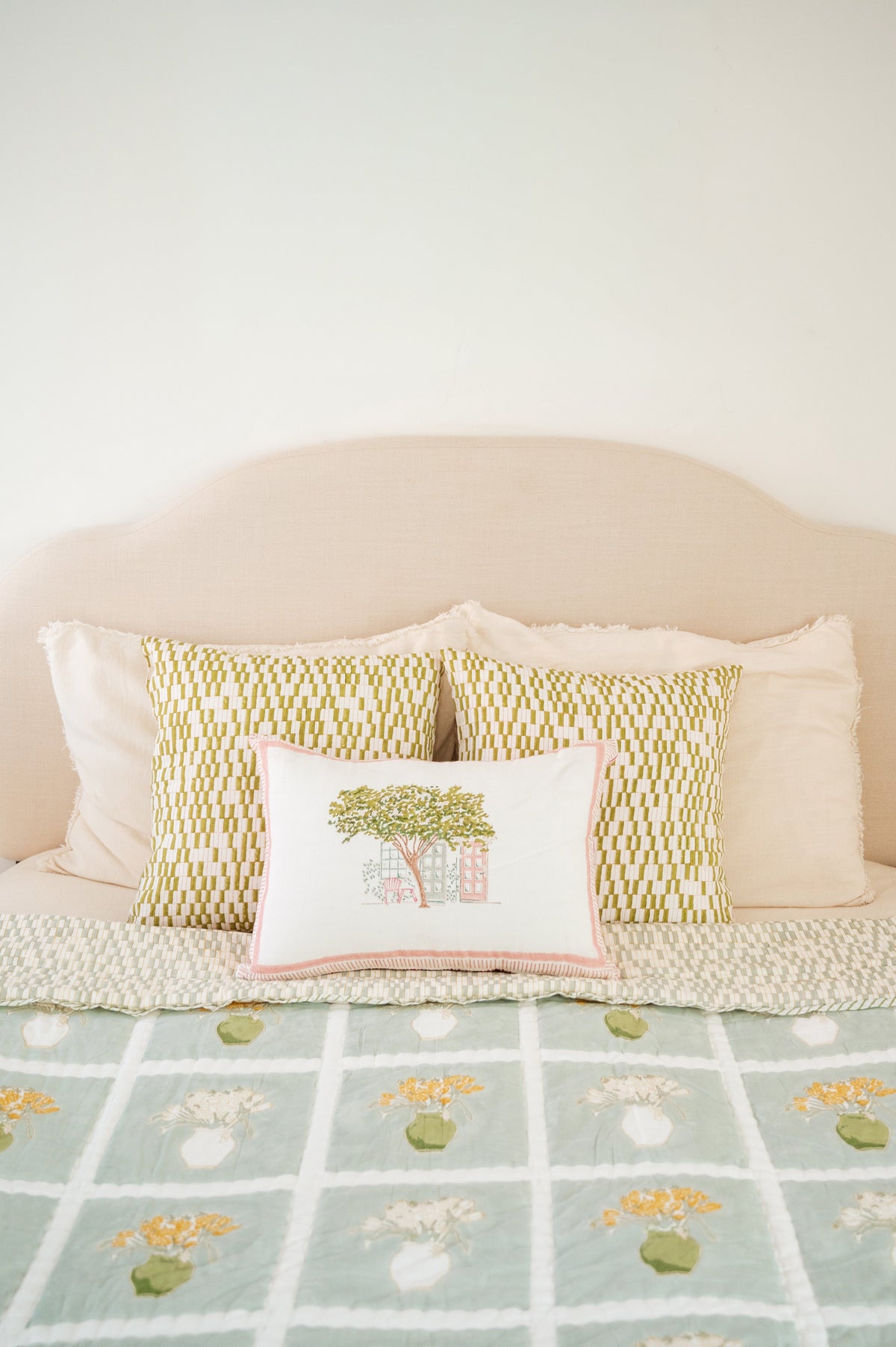 Textured light quilt with two pillows; center pillow has tree graphic print