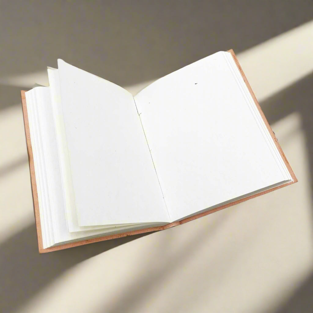 Open brown leather journal showing blank pages and stitched spine