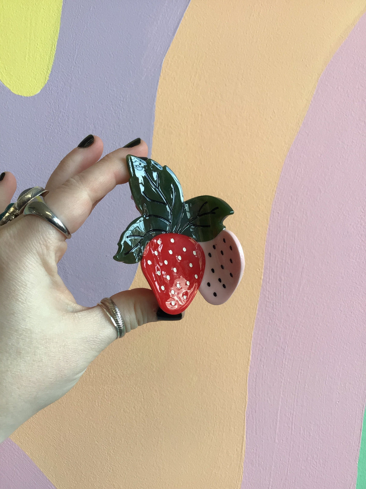 Strawberry-shaped hair claw with red fruit, green leaves, and black seed dots