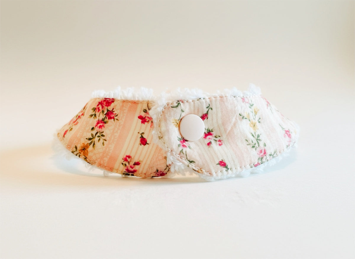 Floral pacifier bib with snap closure and pacifier loop, meadowlark print on light fabric.