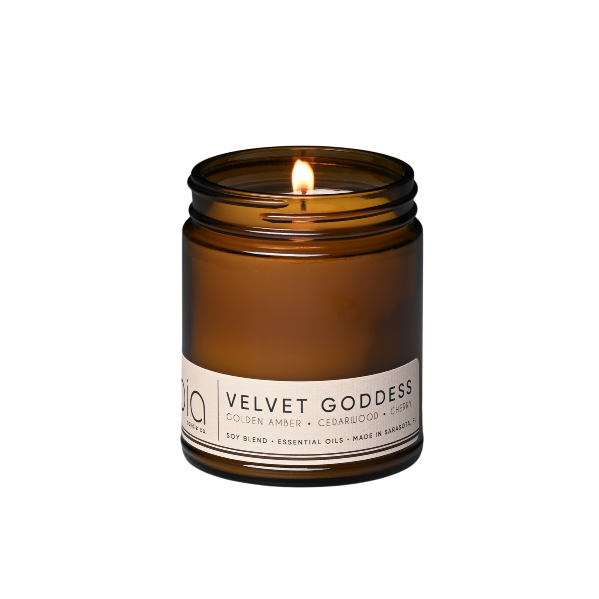 Dark brown glass soy candle jar with two lit wicks and front label