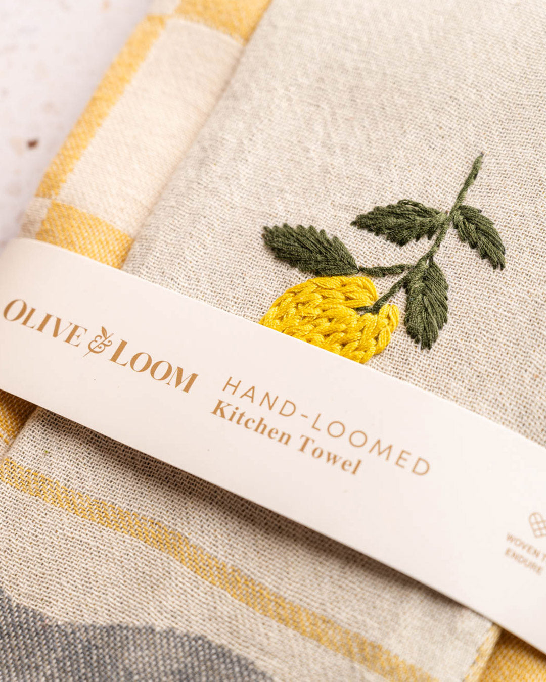 Hand-loomed kitchen towel with lemon-and-leaf embroidery on striped border; label visible