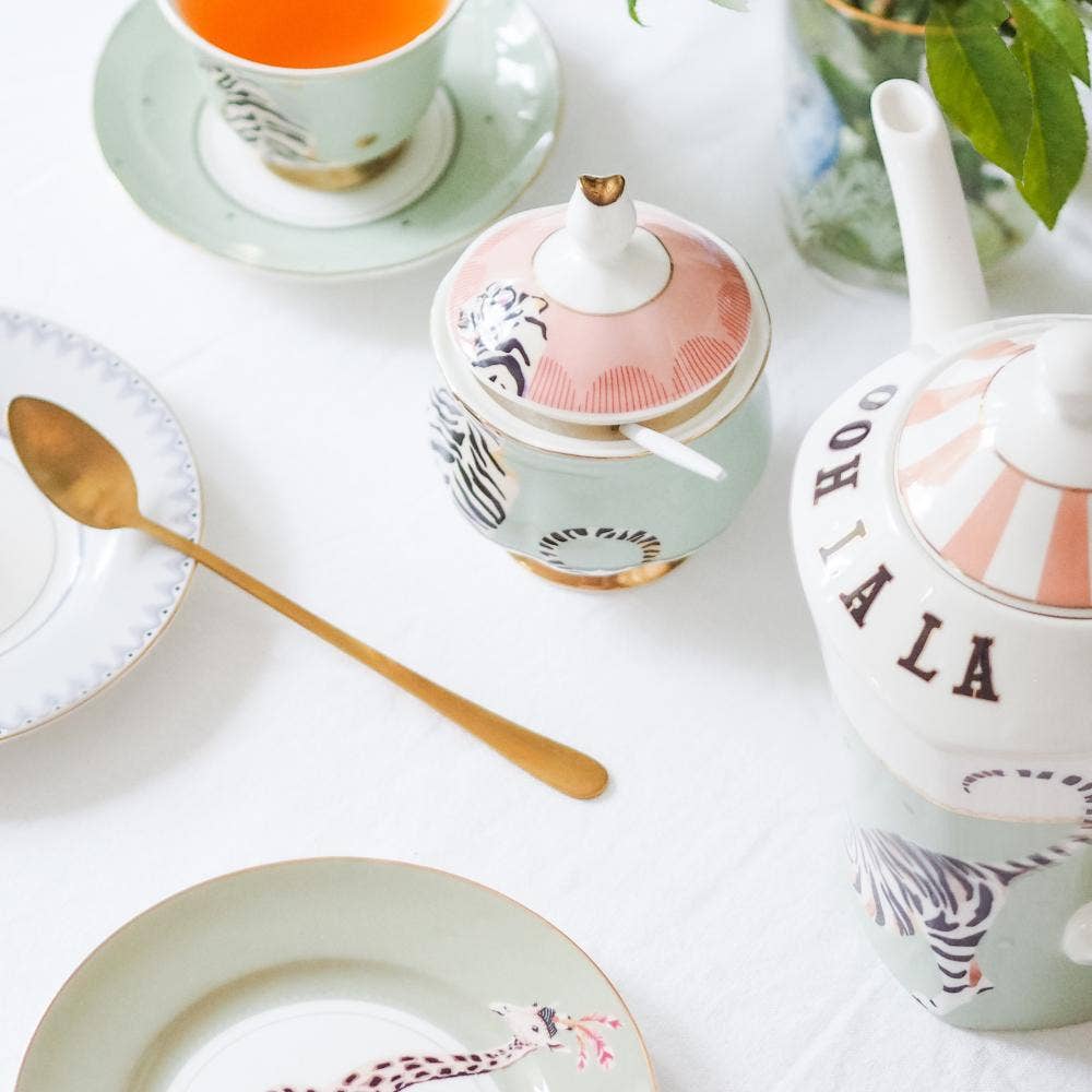 Lidded tiger-print sugar bowl on table with spoon and other ceramics