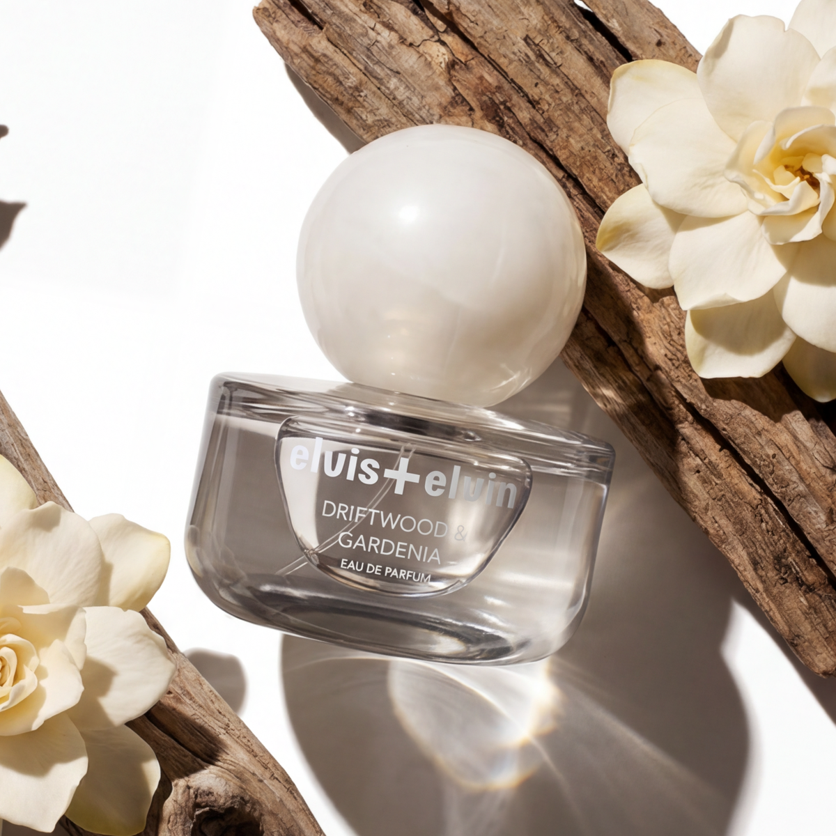 Driftwood & Gardenia eau de parfum bottle on driftwood with white blossoms