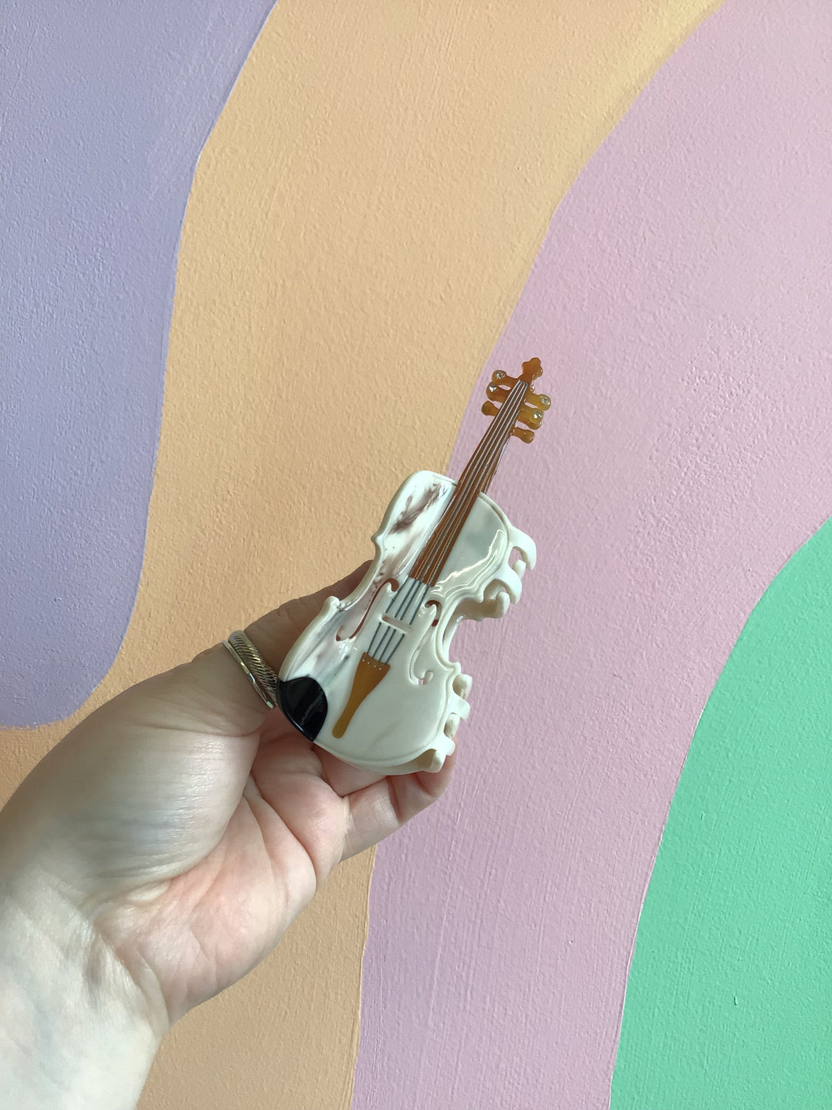 Musical hair claw shaped like a white violin with brown strings and gold details